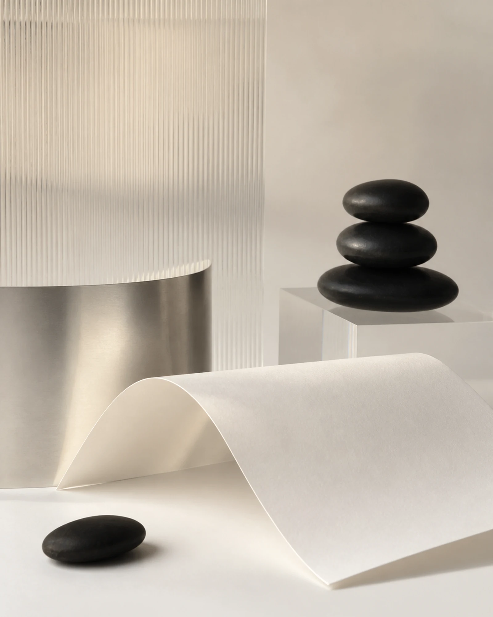 quiet sculptural material study with paper, metal, and black stones