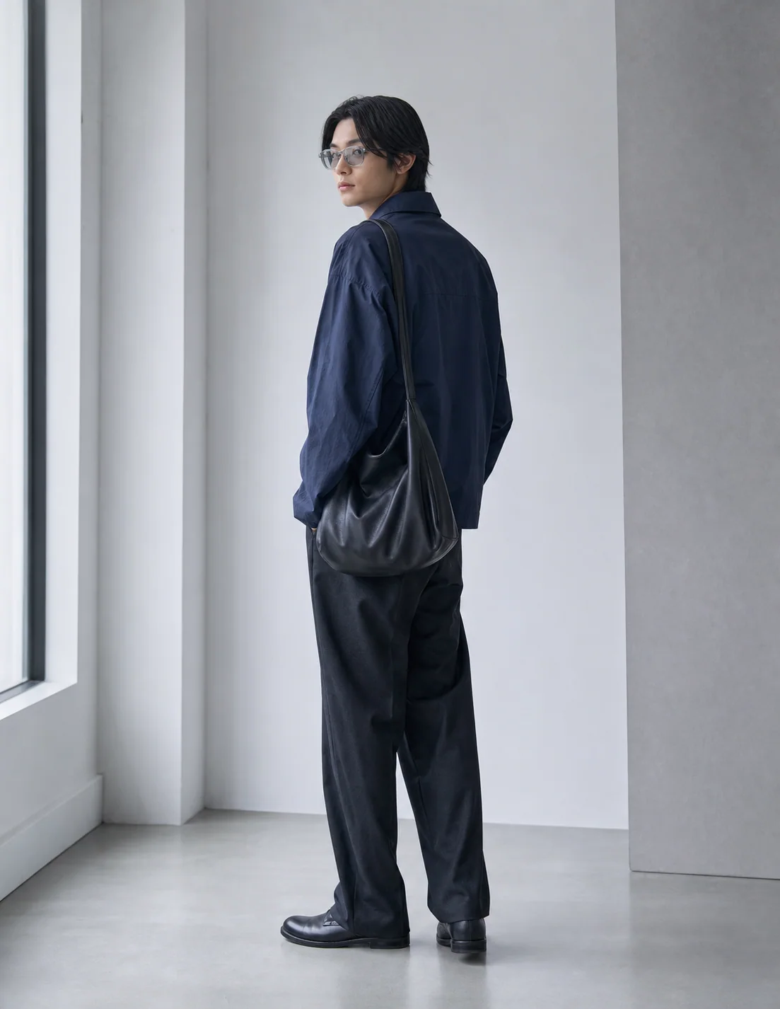Model wearing a navy jacket and black shoulder bag
