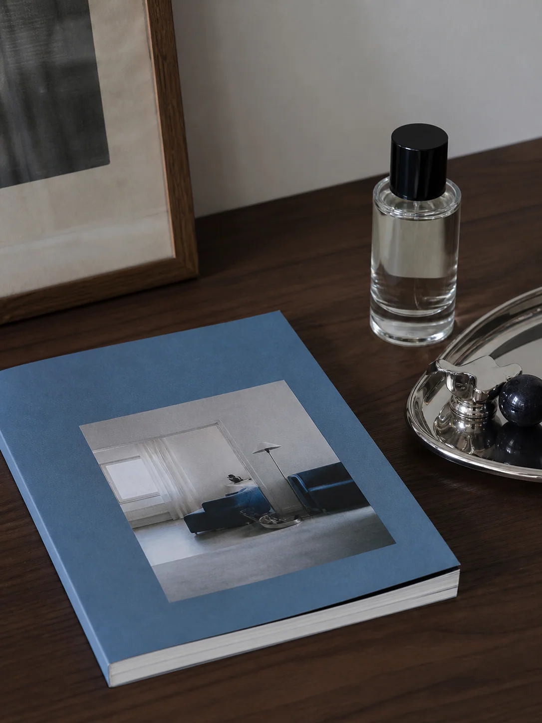 Blue magazine, perfume, and chrome tray on a desk