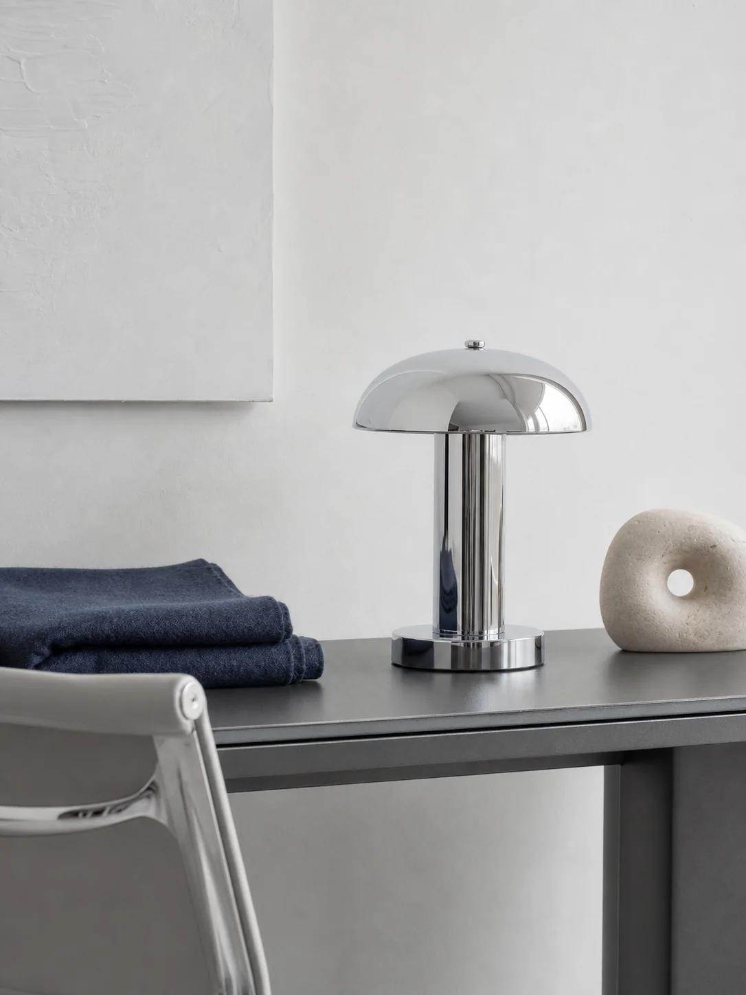 Chrome lamp and navy textile in a quiet room