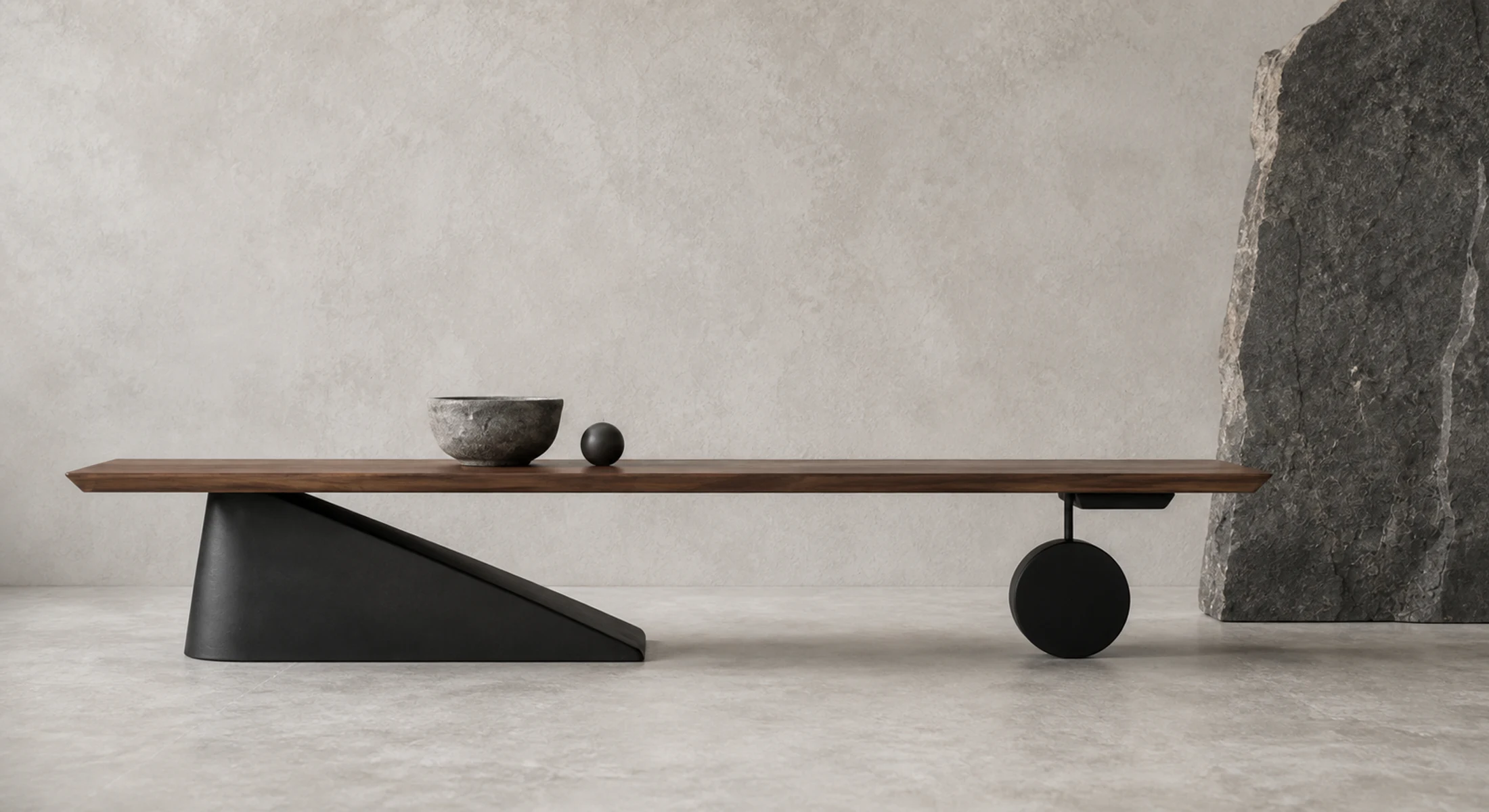 A long walnut table balanced on a black wedge and circular counterweight