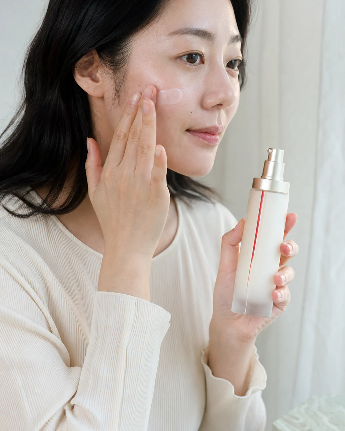 Person applying KINUVE essence with visible skin texture