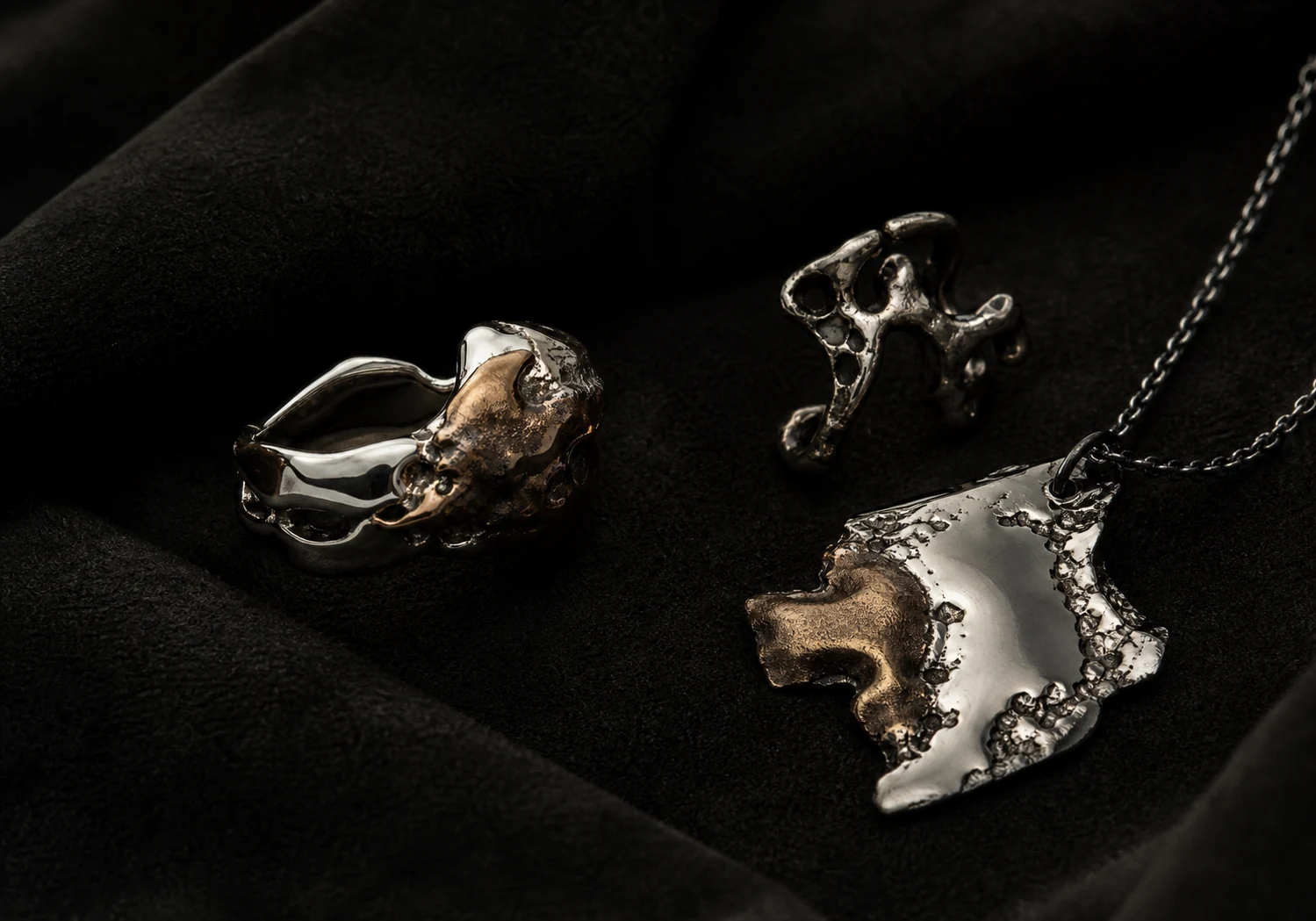 ODD METAL jewelry arranged on black fabric.