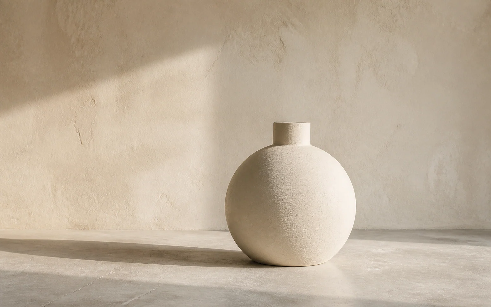 Minimal ceramic vessel in a quiet warm-toned studio.